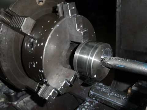 Pièce cylindrique serrée dans le mandrin d’un tour, avec un outil dans son axe.