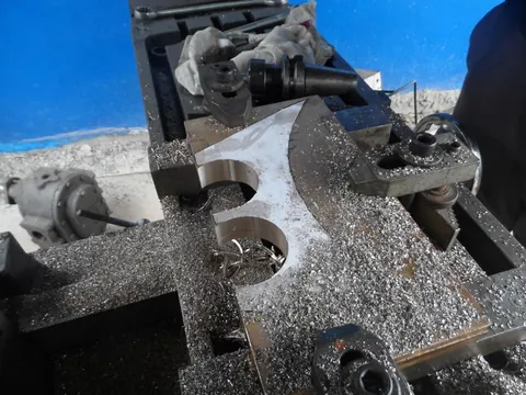 Pièce bridée sur une table de machine-outil, avec des copeaux autour de la zone de travail.